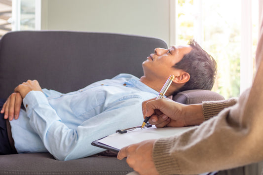 A woman in a deep, relaxed state during a hypnosis session for karmic release, guided to let go of emotional blocks, past traumas, and energetic burdens in a peaceful healing space